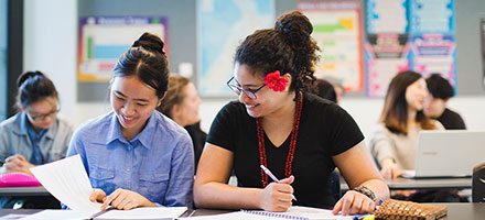 Two smiling students working in class